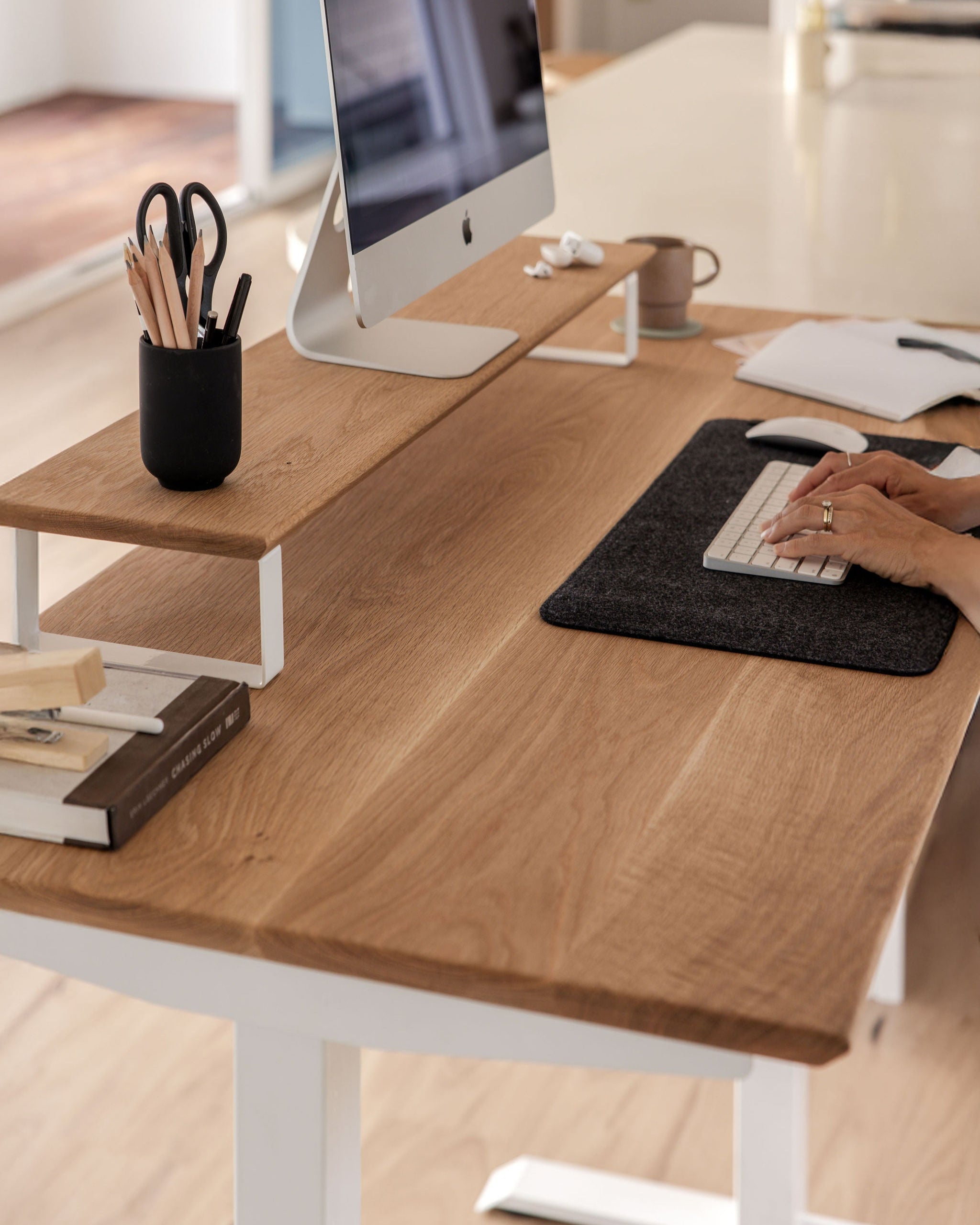 Upwood white oak monitor riser elevating iMac display with matching desk setup, featuring minimalist organization and ergonomic workspace accessories including pencil holder and keyboard mat